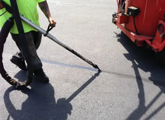 A man using a power washer to clean a parking lot.