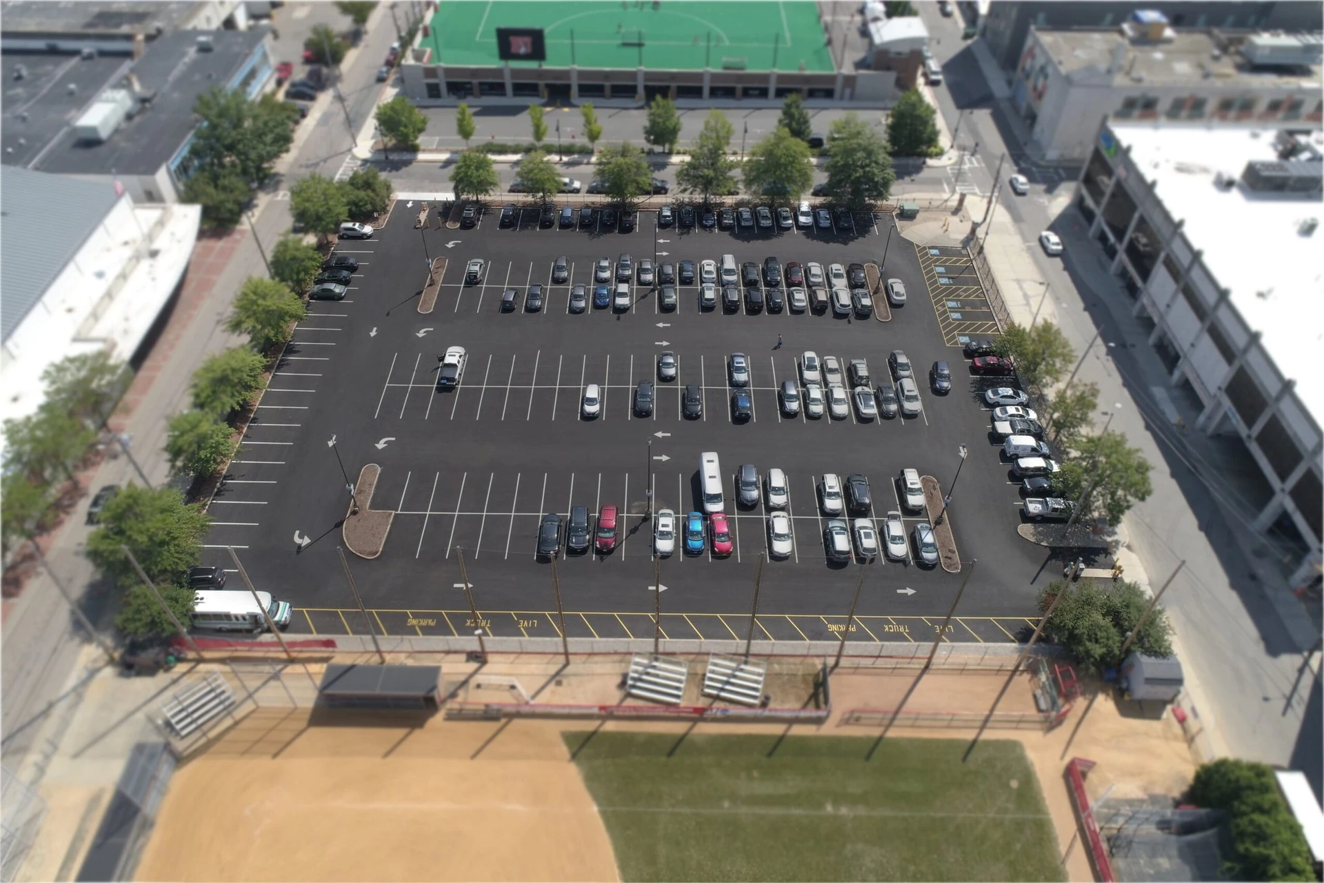 An aerial view of a parking lot and a baseball field.